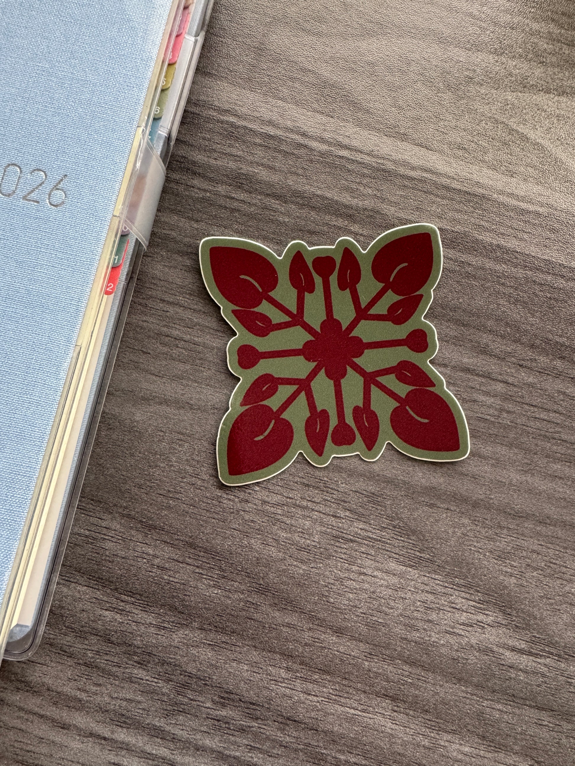 An anthurium quilt shaped sticker placed on a grey wooden desk
